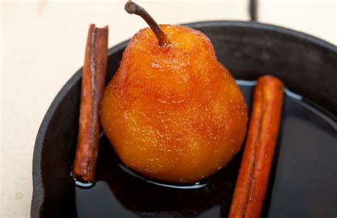 Una ciotola con pere cotte, guarnite con cannella e un filo di sciroppo