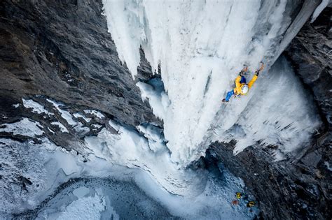 Arrampicatore su cascata di ghiaccio con piccozze e ramponi