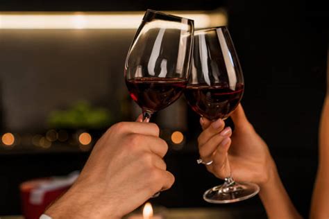 Uomo e donna che brindano con bicchieri di vino rosso