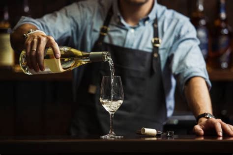 un sommelier che versa vino in un calice elegante