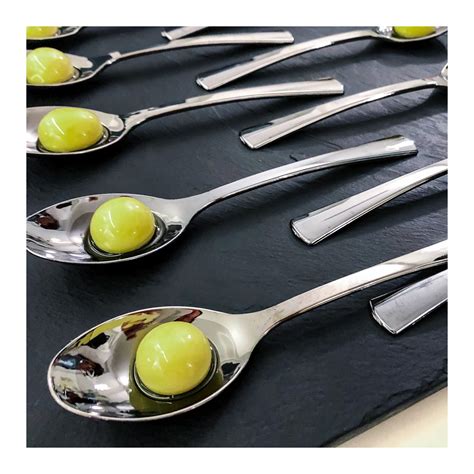 Un'oliva sferificata su un cucchiaio decorativo