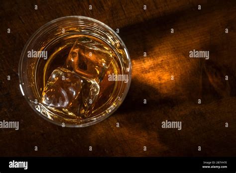 Un bicchiere di whisky ambrato con un cubetto di ghiaccio