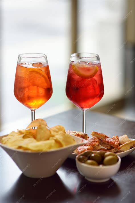Una moderna interpretazione di un aperitivo italiano con un bicchiere di cocktail colorato e stuzzichini gourmet su un tavolo elegante.