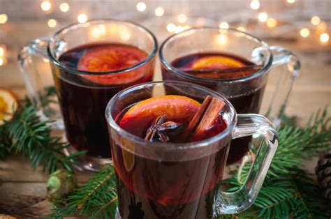 Immagine di una tazza fumante di Vin Brulè decorata con una stecca di cannella e una fetta d'arancia.