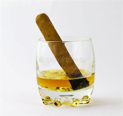 Un bicchiere di whisky ambrato con un sigaro accanto
