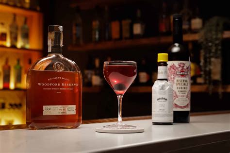 Ingredienti per un Manhattan: bottiglia di Rye Whiskey, Vermouth Rosso, Angostura e una ciliegia