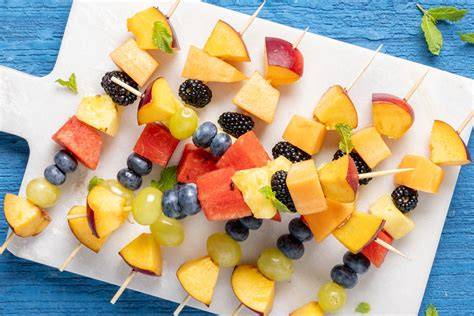 Spiedini di frutta colorati con pesche, melone e frutti di bosco