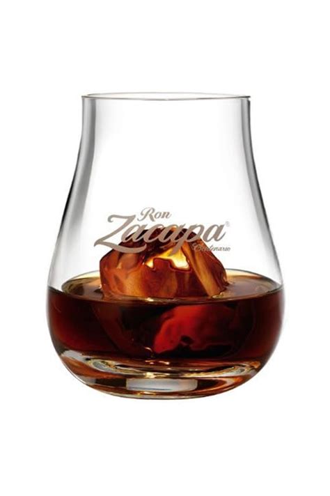 Un bicchiere da degustazione di rum ambrato accanto a pezzi di cioccolato fondente